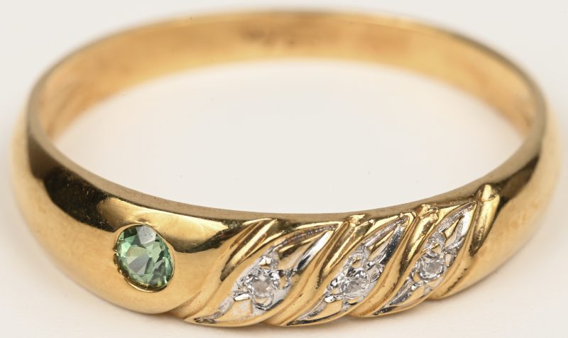 Een 18 kt geelgouden ring bezet met drie briljantjes en een groene kleursteen.