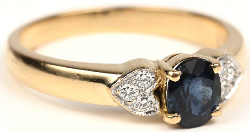 Een 18 kt geelgouden ring bezet met een centrale saffier van +- 0,50 ct. en briljanten met een gezamenlijk gewicht van +- 0,10 ct.