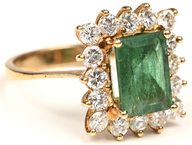 Een 18 kt geelgouden ring bezet met briljanten met een gezamenlijk gewicht van +- 1,30 ct. en een smaragd van +- 2 ct. Met certificaat.