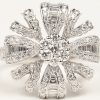 Een 18 kt witgouden bloemvormige ring bezet met briljanten en diamant baguetten met een gezamenlijk gewicht van +- 1,25 ct.