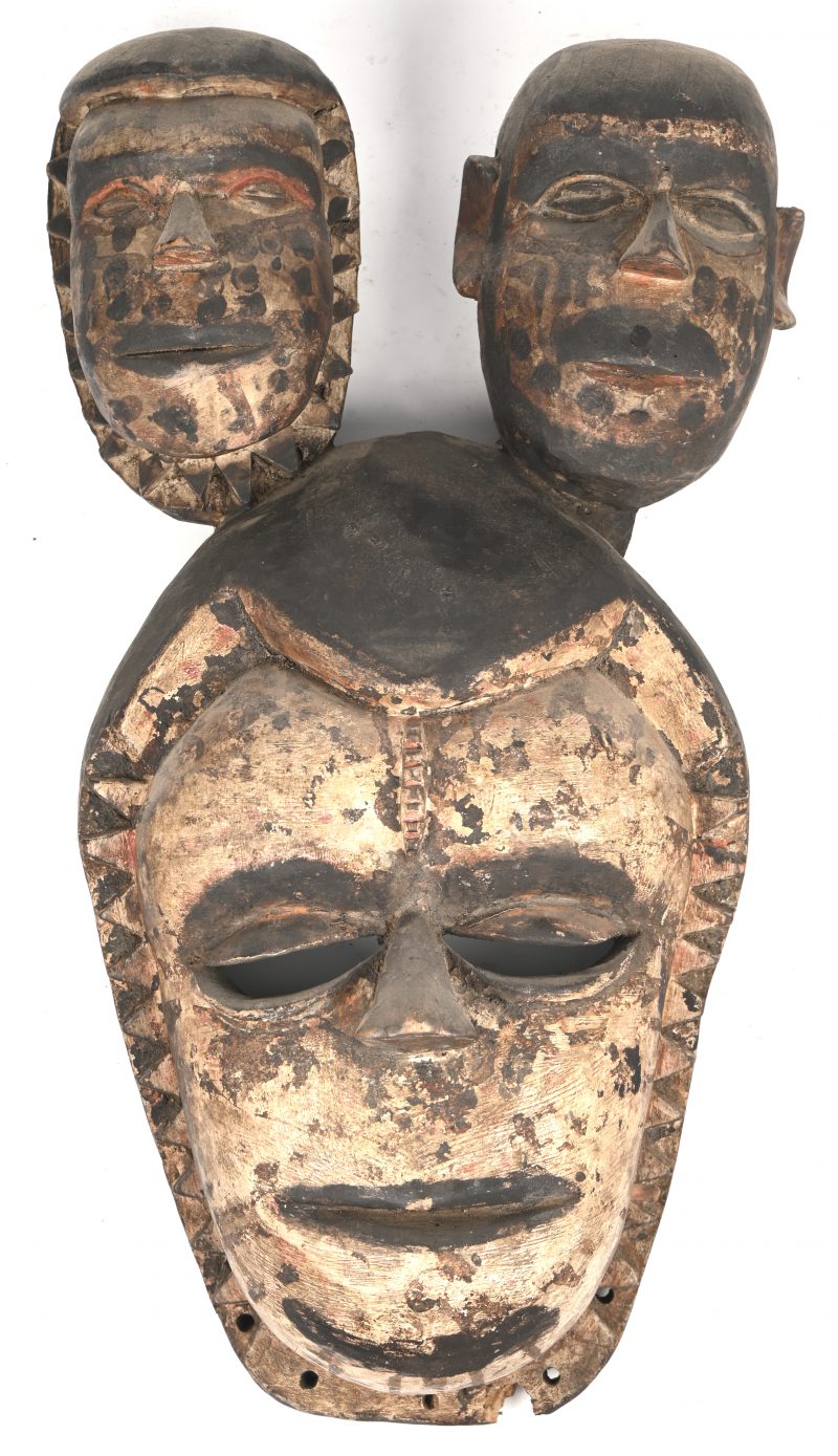 Een houten helmmasker getooid met twee kleine hoofden. Mogelijk Kameroen.