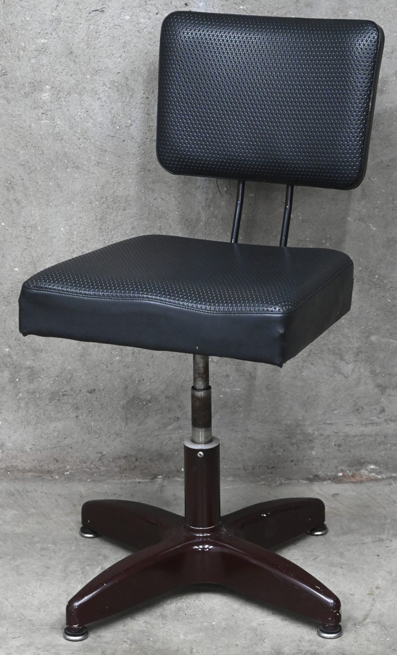 Een industriele stijl vintage bureaustoel in metaal en zwart kunstleder. Heeft een kleine schade aan de achterkant van de zitting.