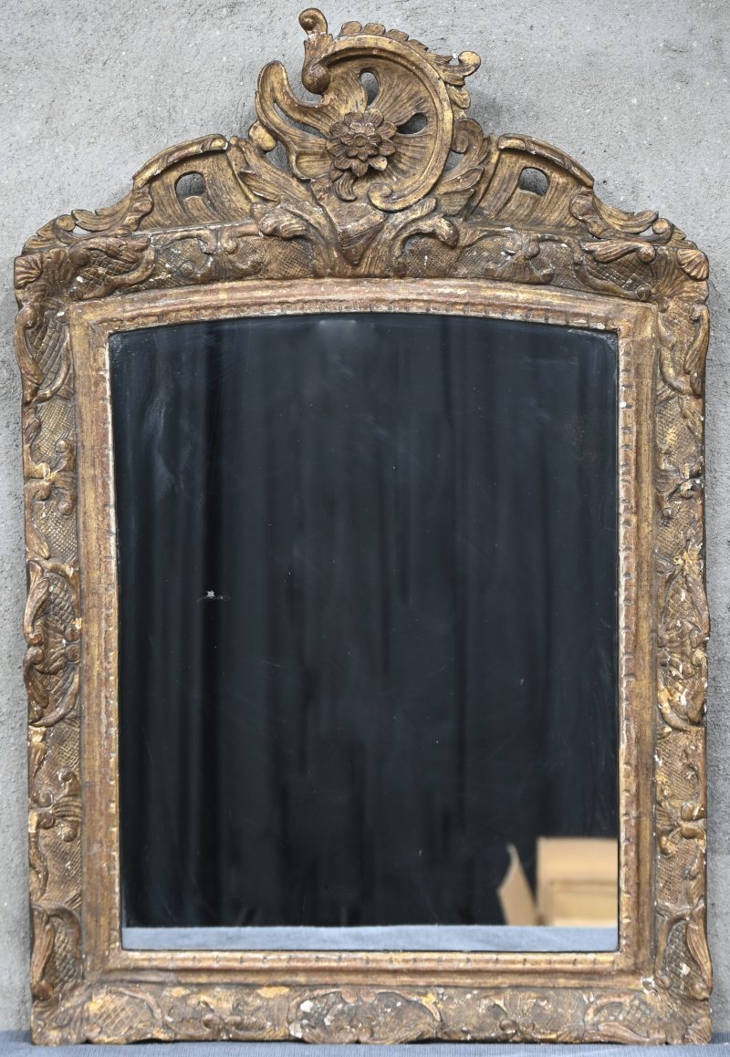 Een Louis XV spiegel in polychroom houten kader met floraal gesculpteerd ornament. Medio 1750.