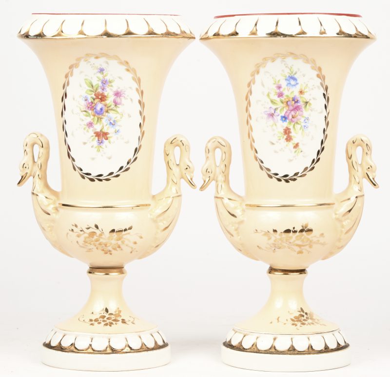Een paar Frans porseleinen vazen met floraal decor, vergulde details en armen in zwaan vorm. Onderaan gemerkt. Begin 19e eeuw.