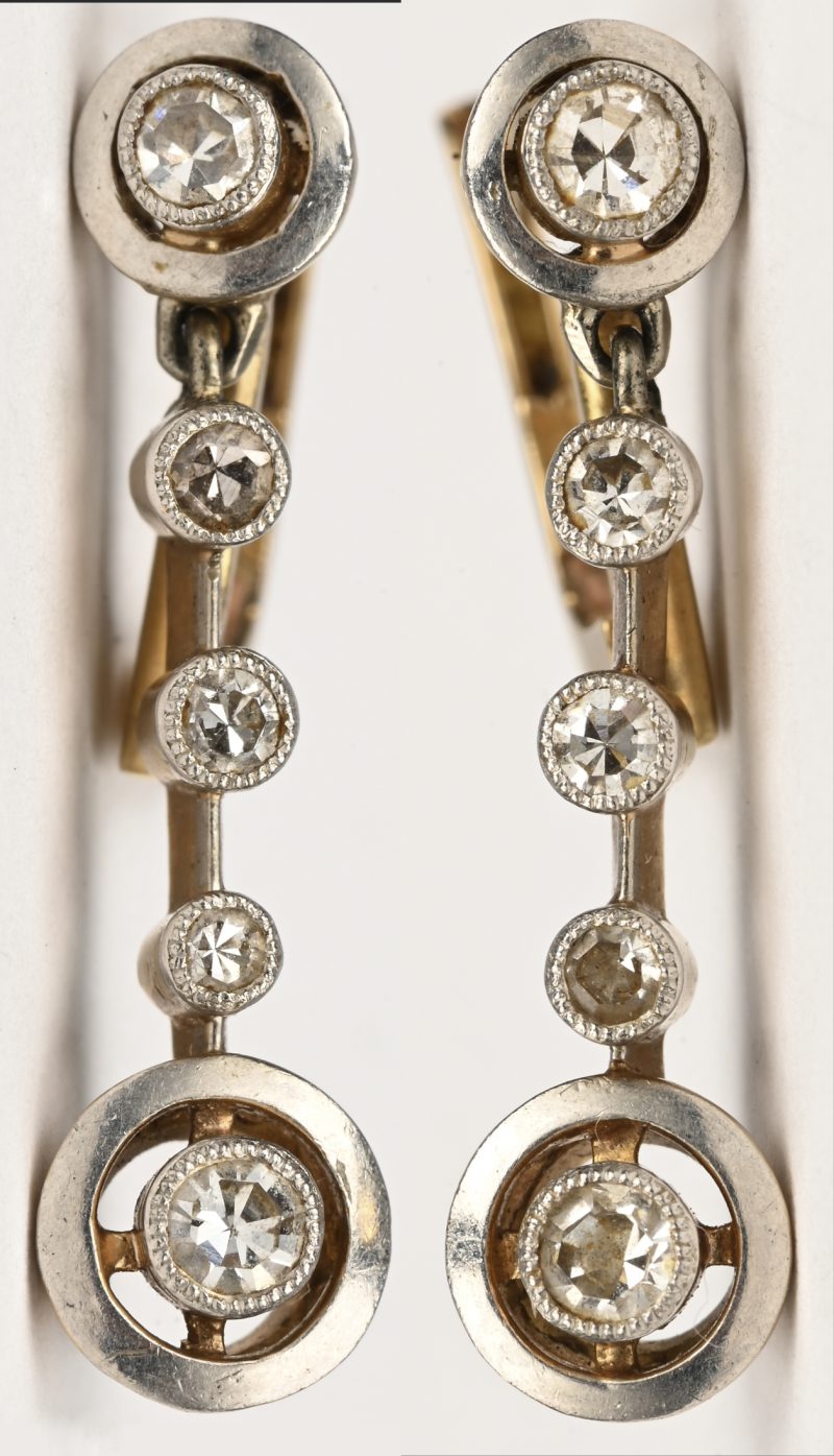 Een paar 18 kt wit en geelgouden oorbellen bezet met diamanten met een gezamenlijk gewicht van +- 0,30 ct.