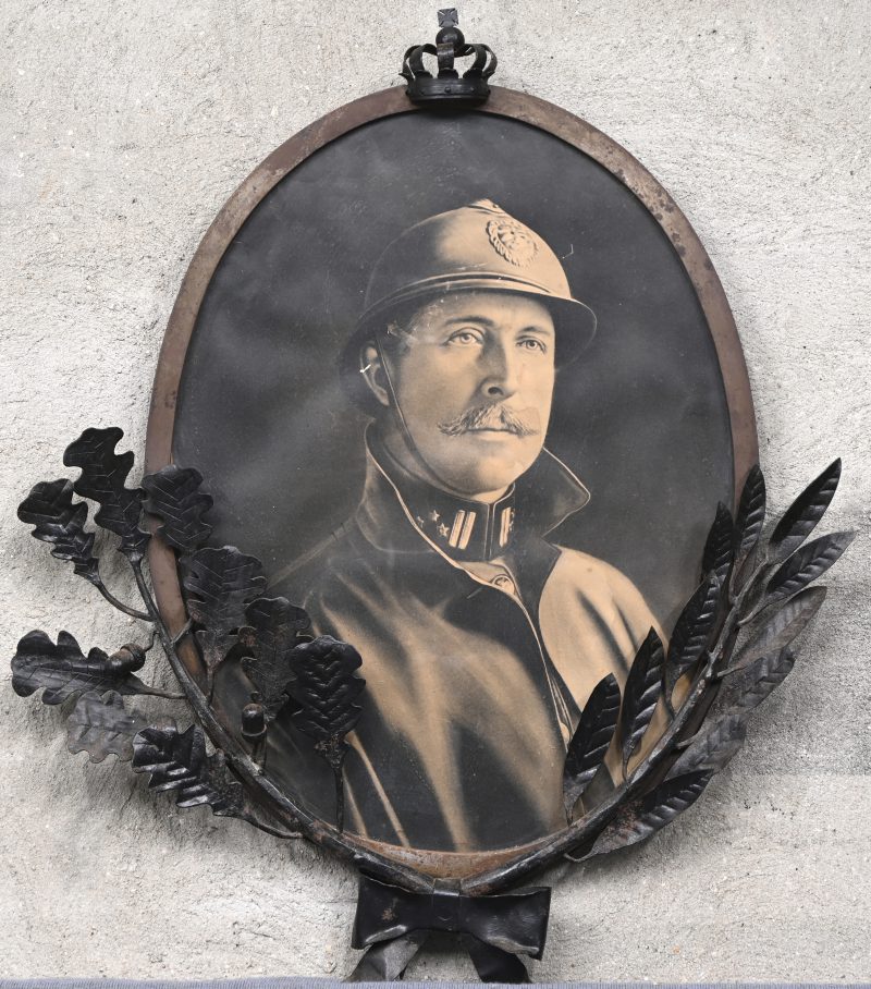 “Albert I met Casque Adrian”. Een in metalen frame gekadreerde foto met gietijzeren kroon en eikentak ornamenten versierd.
