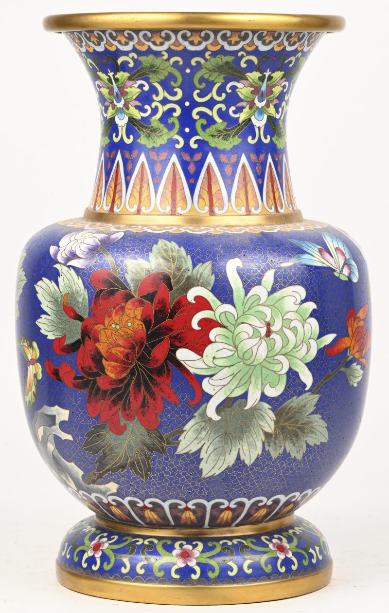 Een cloisonné vaas met blauwe achtergrond en een decor van bloemen.