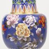 Een cloisonné vaas met blauwe achtergrond en een decor van bloemen.