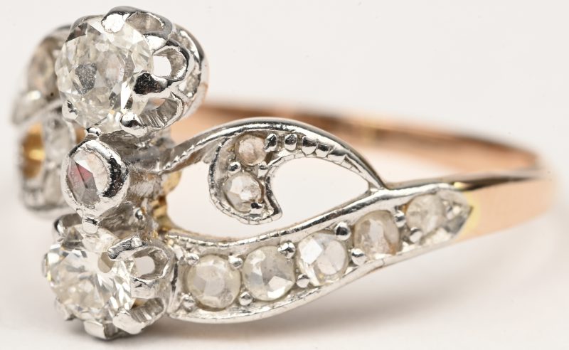 Een 18 kt wit en geelgouden ring bezet met twee briljanten en diamanten oude slijp met een gezamenlijk gewicht van +- 0,80 ct.