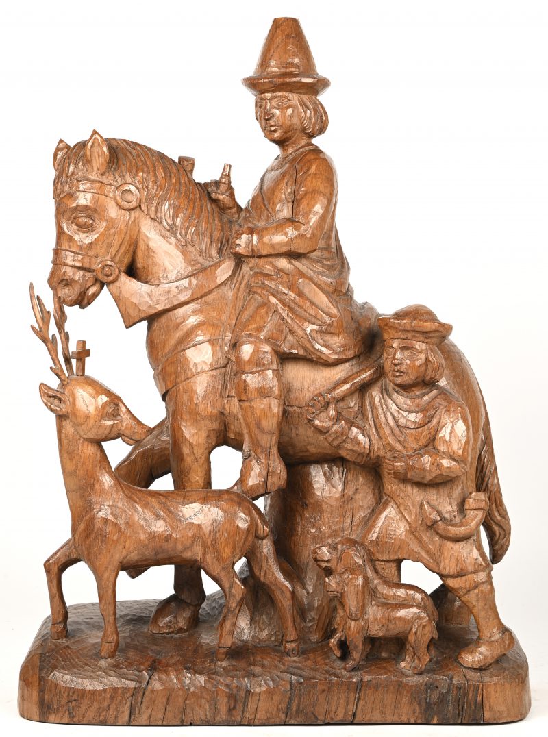 Een groot massief eikenhouten beeld van Sint Hubertus te paard met hertje, een man en twee honden.