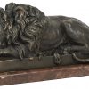 Een paar uit brons gesculpteerde beelden van leeuwen in lighouding op marmeren voet. Naar het werk van Milo.
