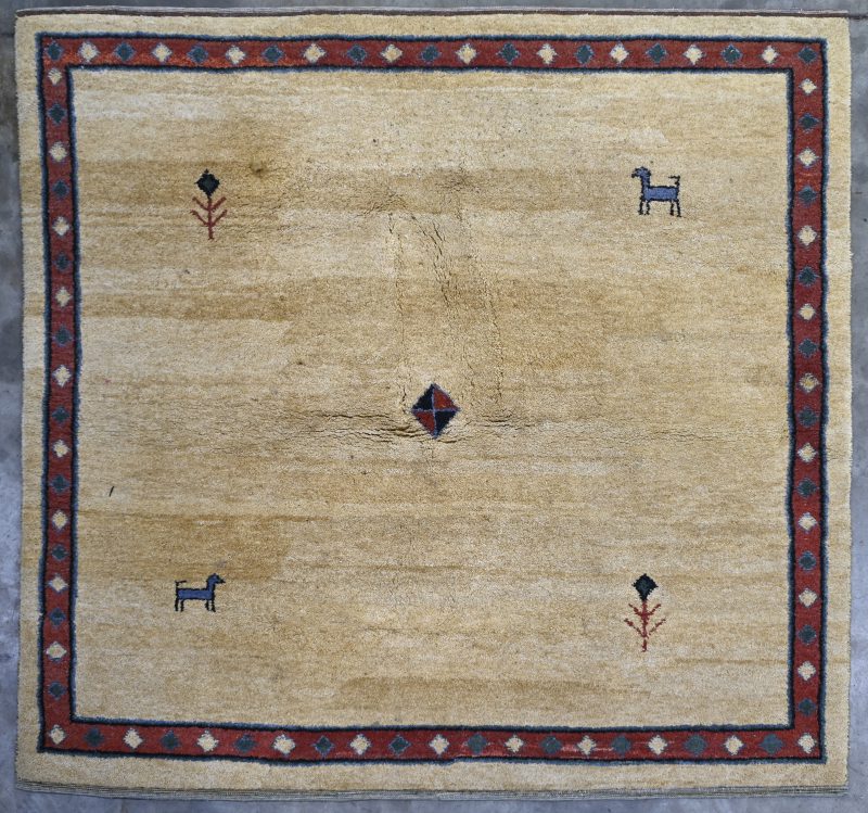 Een wollen tapijt, vierkant, met de afbeelding van lama’s of alcapa’s.