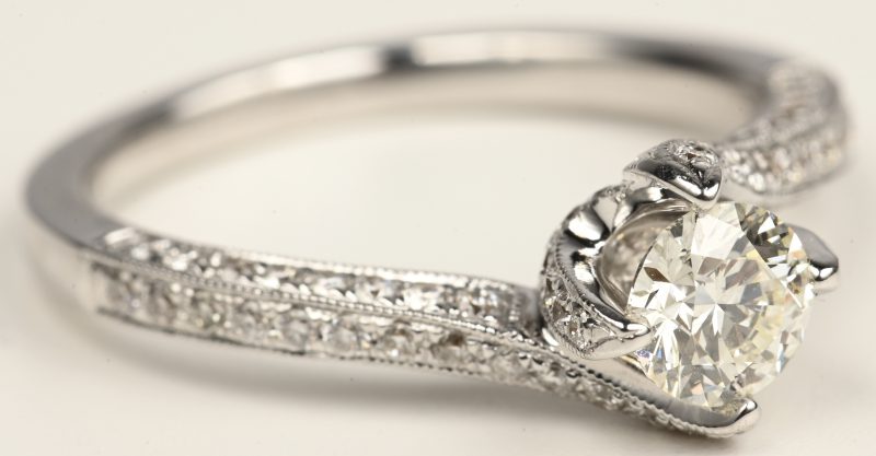 Een 18 kt witgouden ring bezet met een centrale briljant van +-0,50 ct. F VS. En briljanten met een gezamenlijk gewicht van +- 0,53 ct.