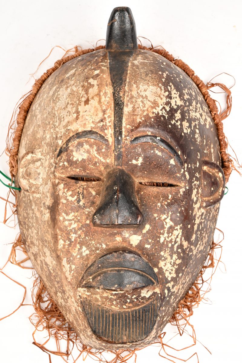 Een gepatineerd uit hout en raffia gesculpteerd masker. Origine Punu, Gabon.