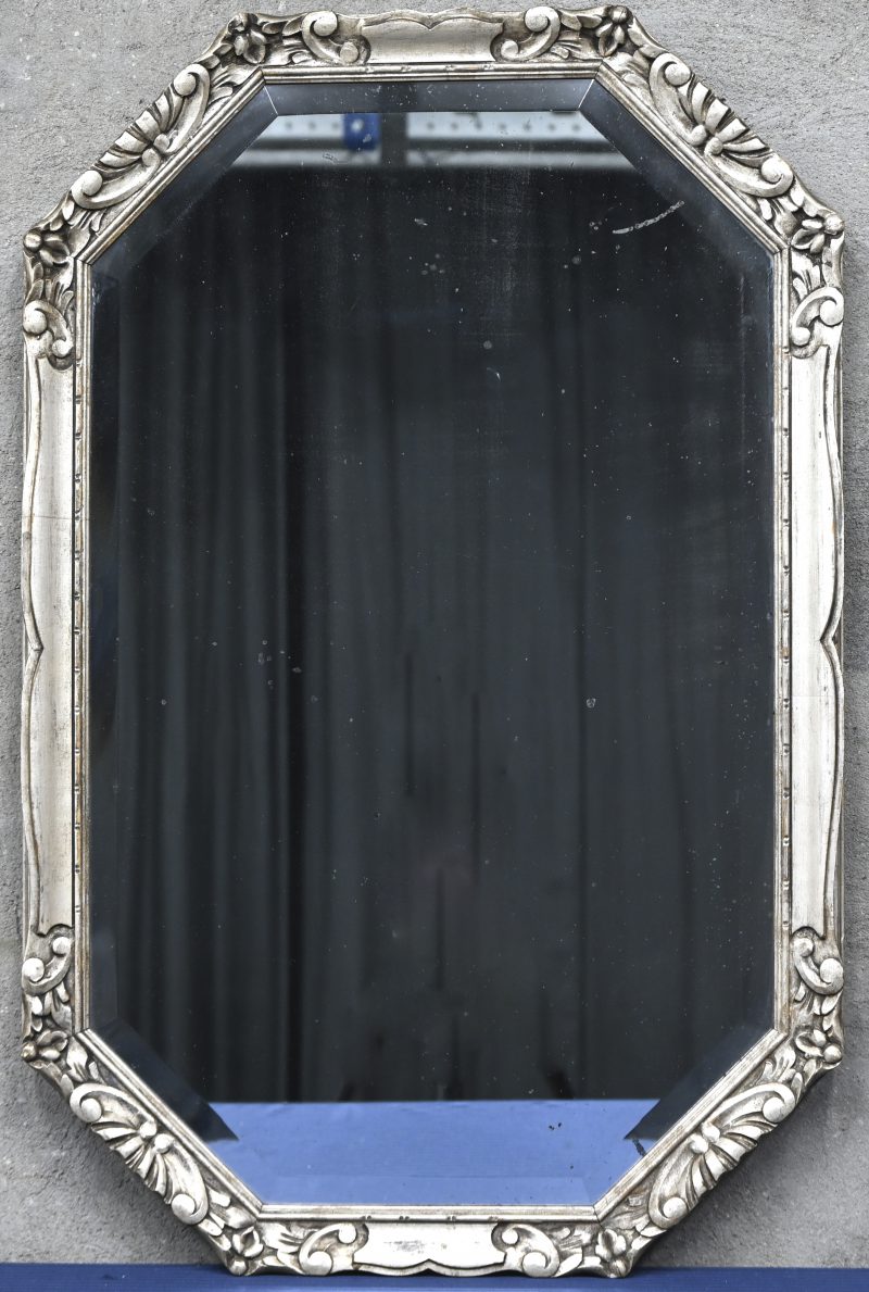 Een geslepen spiegel in een zilverkleurig gepatineerde houten kader. 31-07-1931