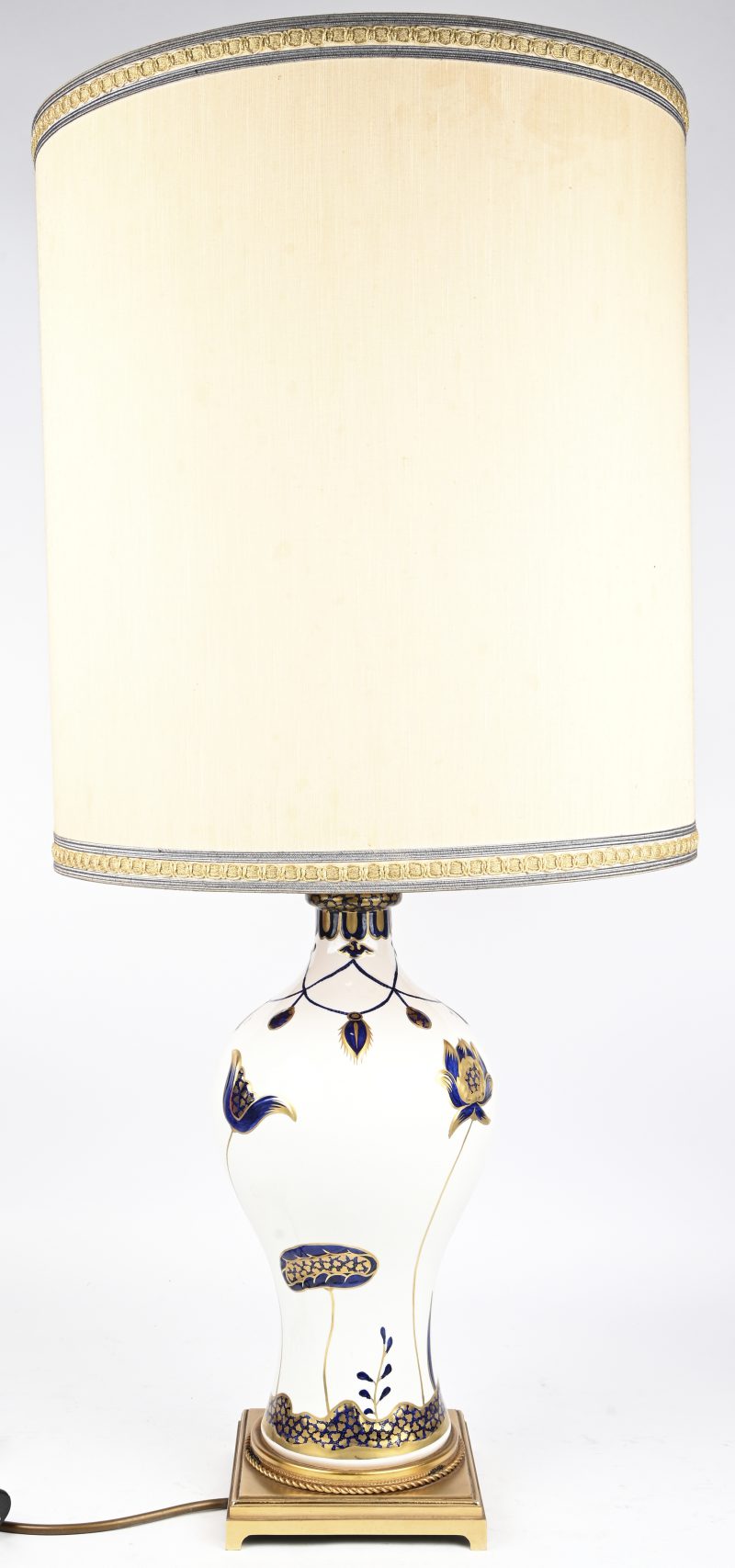 Een porseleinen tafellamp met floraal decor en vergulde voet. In hoogte verstelbaar. Onderaan gelabeld.