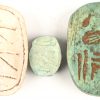 Een lot van 6 Egyptische Scarabeeën in diverse formaten, uit onder meer speksteen en hout gesculpteerd met hiërogliefen. Bijgevoegd 2 Egyptische kralen met inscripties.