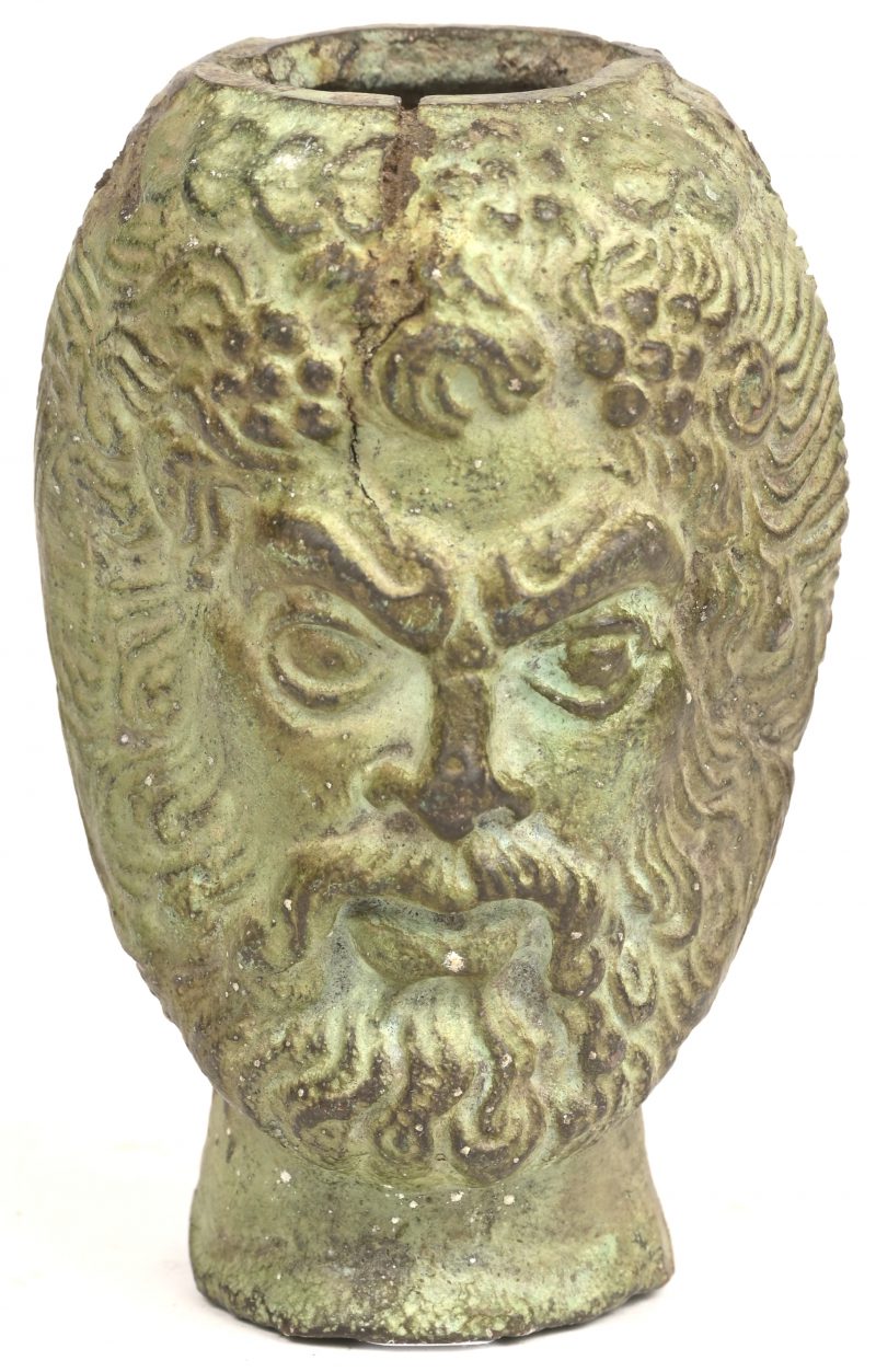 Een brons gesculpteerd hoofd van een bebaard figuur met opening aan bovenzijde en 2 kleine gaatjes aan de zijkant.