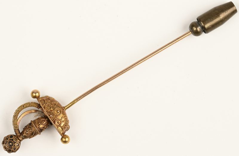 Een 18 K geelgouden speld in de vorm van een zwaard bezet met één saffier en twee robijntjes en twee parels.