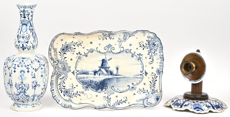 Een wandlicht met koperen montuur, een knobbelvaasje en een schotel met landschap van blauw en wit aardewerk naar Delfts voorbeeld.