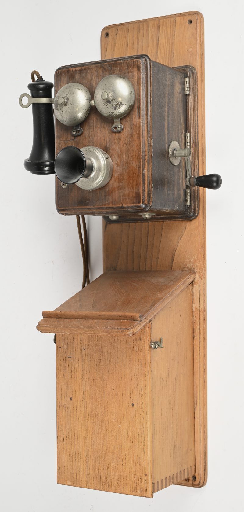 Een oude wandtelefoon op een plank gemonteerd met bakelieten hoorns.