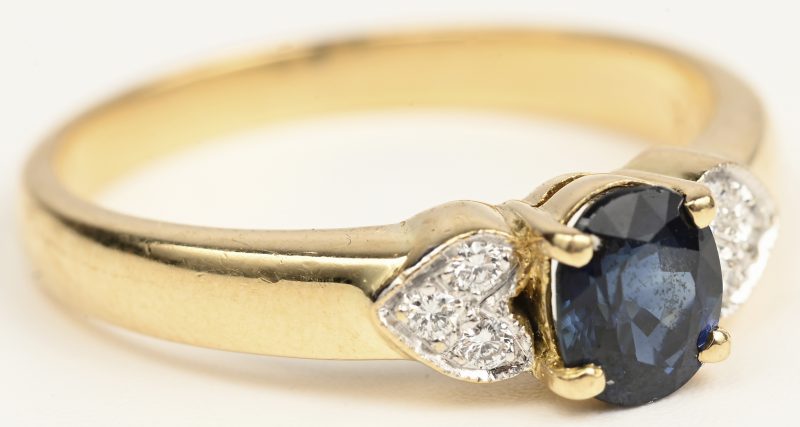 Een 18 K wit en geelgouden ring bezet met zes kleine briljantjes en een centrale safier van +- 0,50 ct.