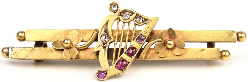 Een 18 K geelgouden harpvormige broche bezet met vier kleine diamantjes oude slijp en vier robijnen met een gezamenlijk gewicht van +- 0,20 ct.