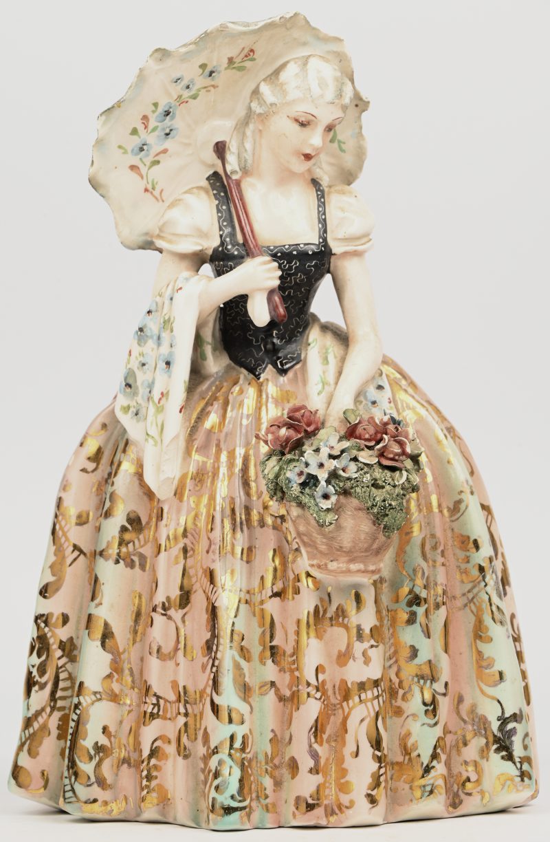 Een porseleinen beeldje van een dame met parasol, bloemenmandje in een hoepelrok, gemerkt Bertolotti Milano. Kleine schilferschade aan enkele bloemetjes.