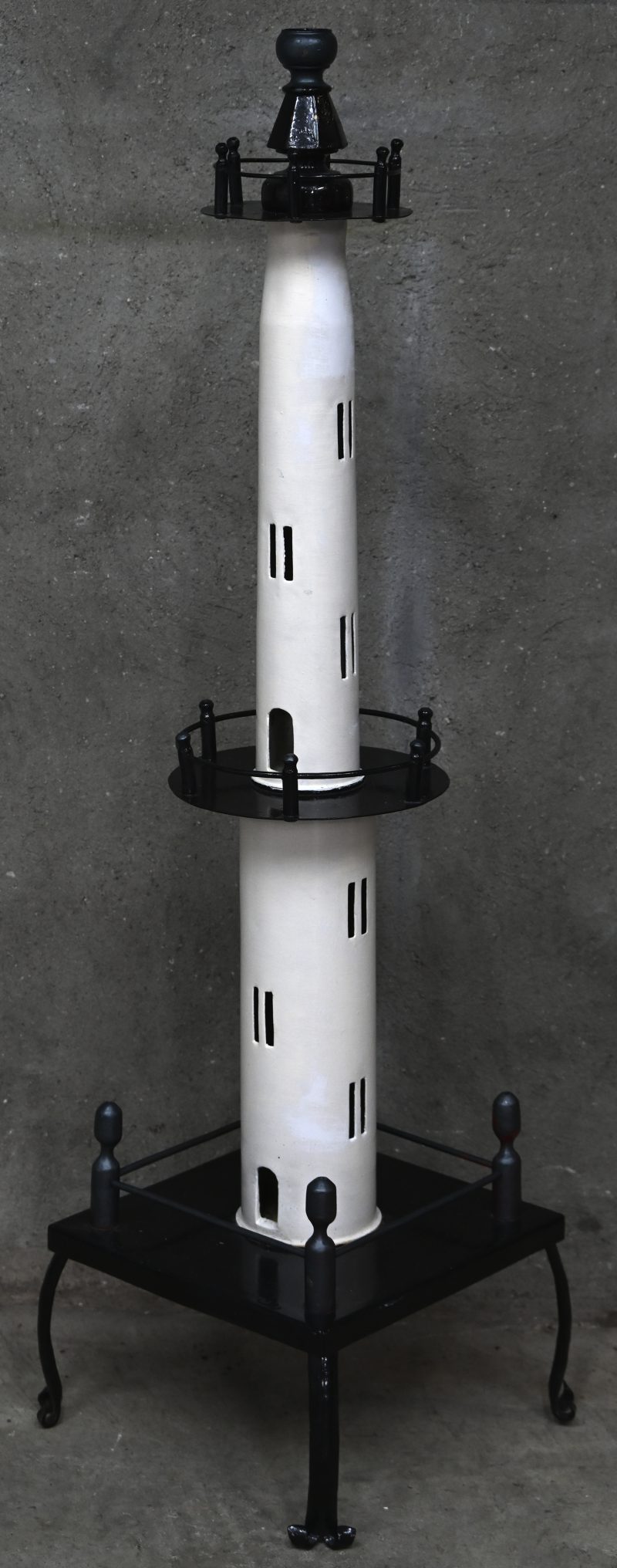 Een lampenvoet van metaal in de vorm van een vuurtoren. Gemaakt van twee obussen.