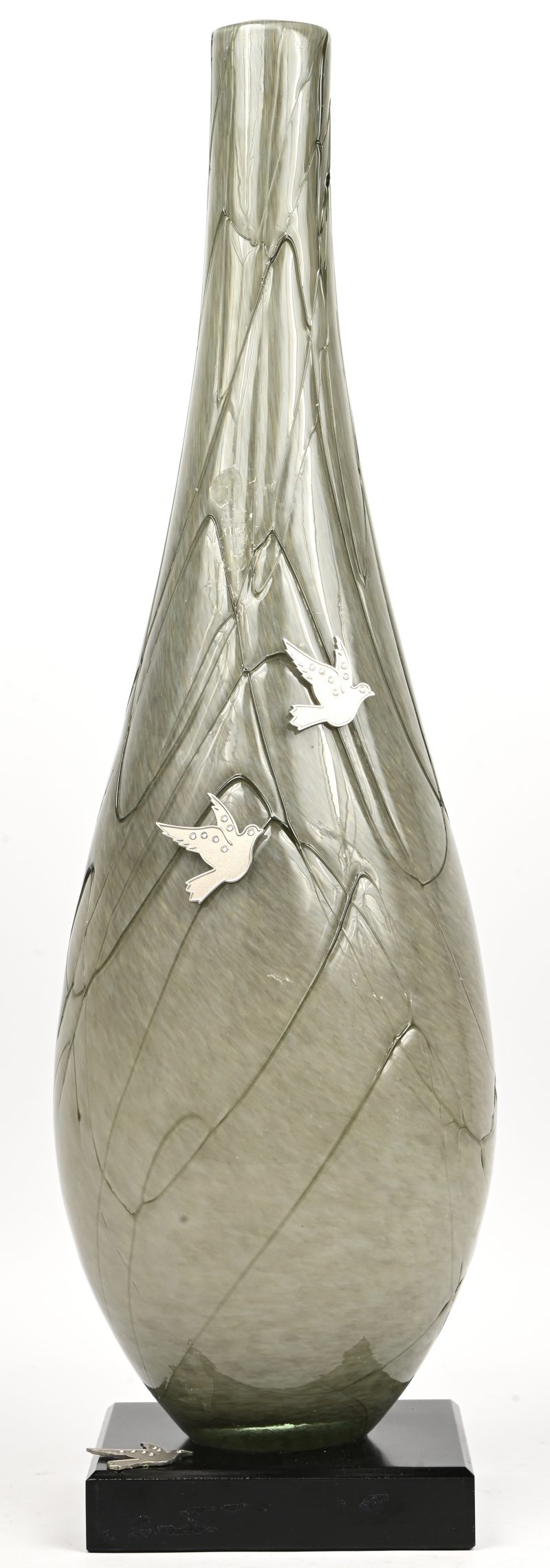 Een uit glaspasta meerkleurige vaas met gesculpteerde lijnen op houten voet. Enkele plaquettes van duifjes op bevestigd.