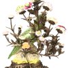 Een kandelaar met twee lichtpunten, uit brons opgebouwd in de vorm plantenranken met porseleinen bloemen rond een centrale papegaai en op bronzen voet in barokke stijl. Onderaan gemerkt.