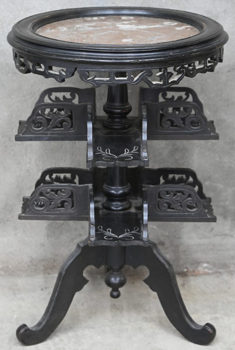 Een chinoiserie piëdestal van gebeeldhouwd zwart hout met rond marmeren blad. Draaiende etagères op twee niveaus, centrale vierpoot. Enkele onderdelen loszittend.