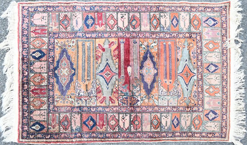 Een Perzisch karpet van wol. Handgeknoopt. Versierd met kleine mirhabs in de rand.