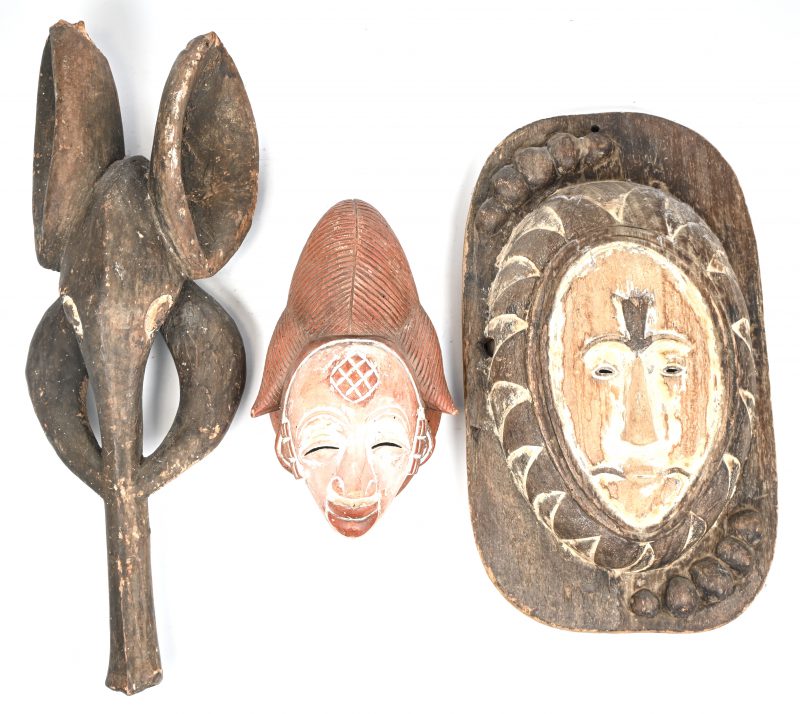 Een lot van drie Afrikaanse houten maskers, een man, een vrouw en een olifant.