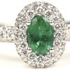 Een 18 kt witgouden ring bezet met centrale smaragd van +- 0,40 ct. En briljanten met een gezamenlijk gewicht van +- 0,75 ct.