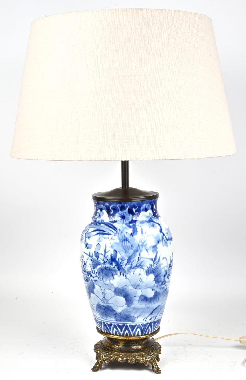 Een lampenvoet van blauw-wit Chinees porselein met een decor van vogels in het landschap. Op een bronzen voet.