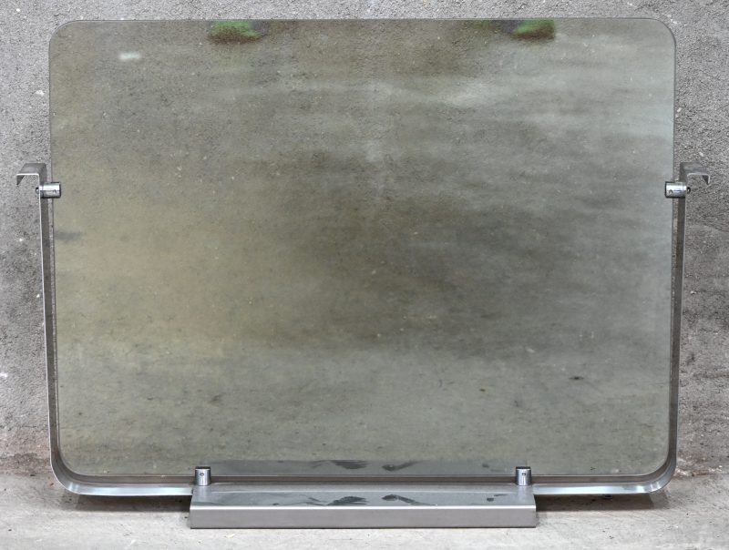 Een glazen haardscherm in gechromeerd metalen frame.