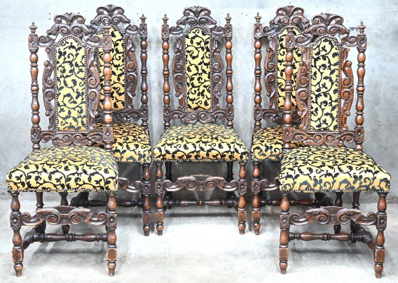 Een set van vijf gesculpteerde eikenhouten stoelen met een stoffen bekleding in goud met zwarte zwierige flora.