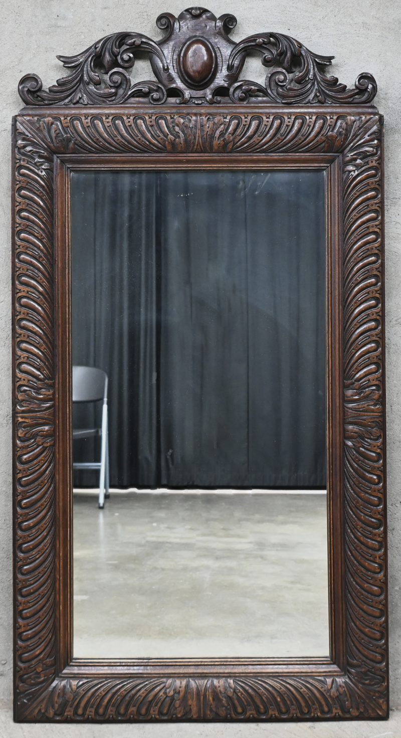 Een spiegel in een eikenhouten gesculpteerde kader.
