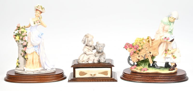 Een lot van 3 meerkleurige beeldjes uit kunsthars op houten voetstuk, bestaande uit een dame met hoed in floraal decor getiteld “Constance”, een vrouw met kind en kar getiteld “Flower Cart”, dewelke door The Leonardo Collection. En een kindje met teddybeer op schuifdoosje, gemerkt Del Vecchio.