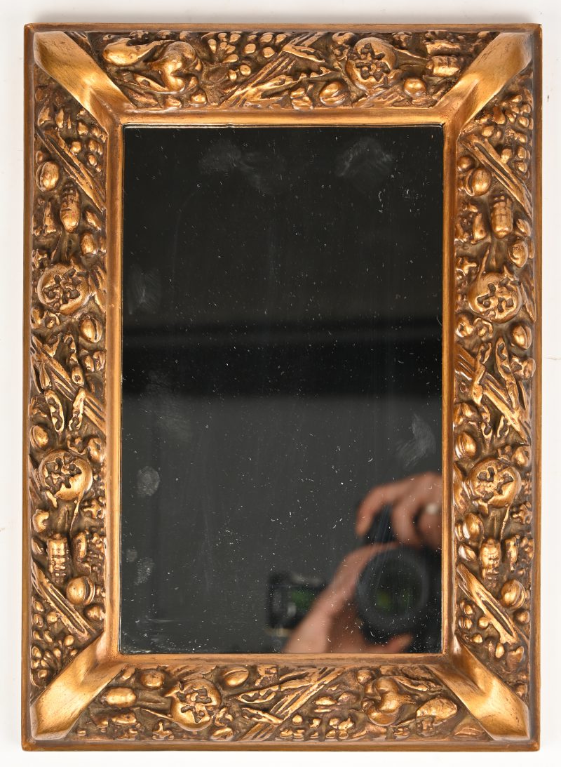 Een spiegeltje in een rijkelijk versierde vergulde kader.