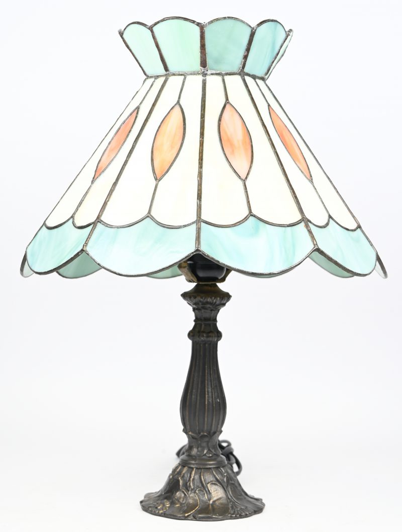 Een tafellamp met een kap in glas en lood in de stijl van Tiffany.