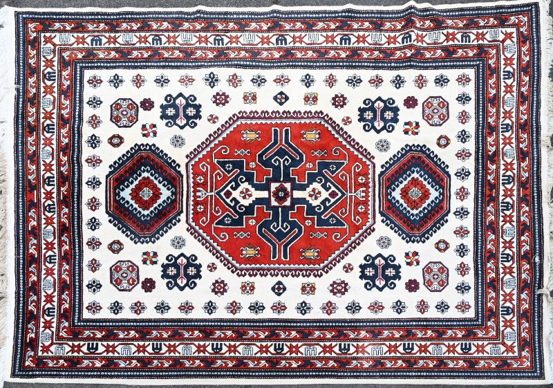 Een Perzisch handgeknoopt tapijt met meerkleurig geometrisch patroon.