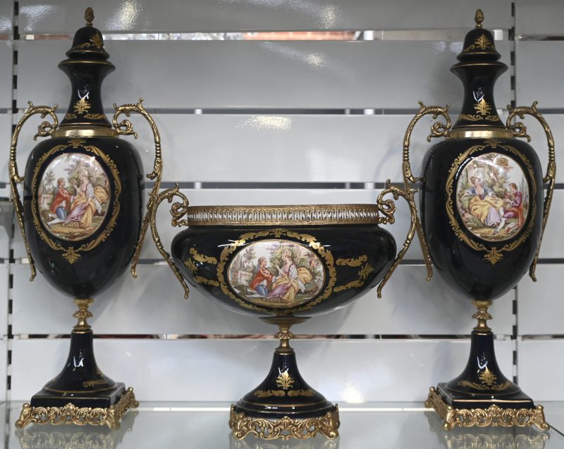 Een driedelig kaststel in porselein. Met romantisch handgeschilderd decor ‘Louis XV.’ ‘Dècorè Limoges’. Eén deksel beschadigd.