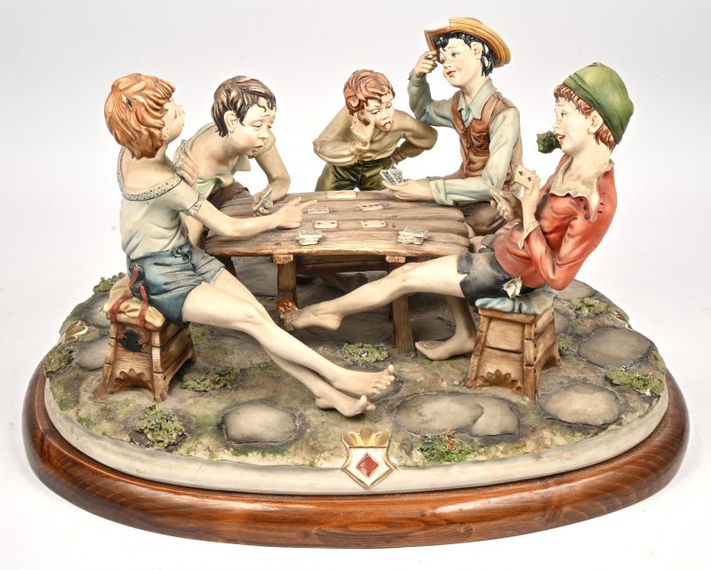 Een groot Capodimonte beeld van vier jonge kaartspelers en een toeschouwer. Gesigneerd en genummerd. Minieme schade.