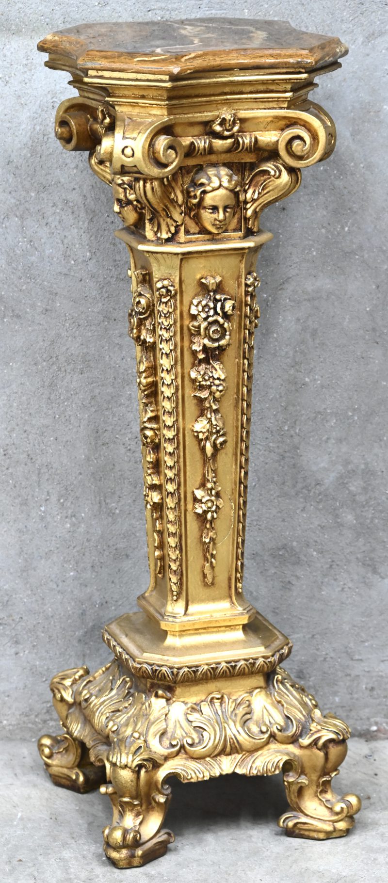 Een piëdestal in goudkleurig kunststof met een marmeren blad.