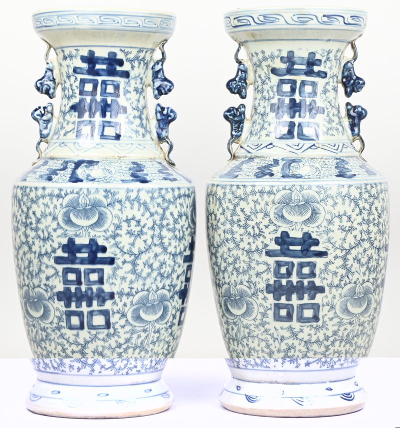 Een paar Chinees porseleinen vazen, blauw-wit met karakters en floraal decor.