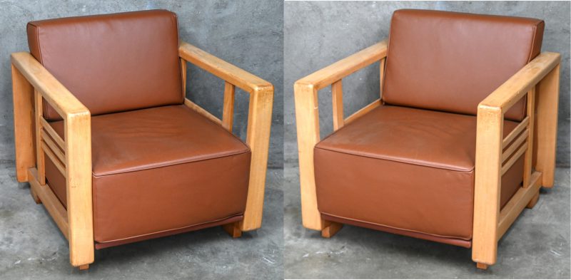 Een paar vintage design armfauteuils met lederen zitting en houten frame.