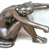 Een bronzen salontafel van een zittend, naakte vrouw, dewelke een glazen ovaal tafelblad vasthoudt.