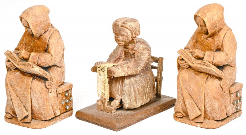 Een houten beeldje van een kantklosster en twee gipsen beeldes van lezende monniken.